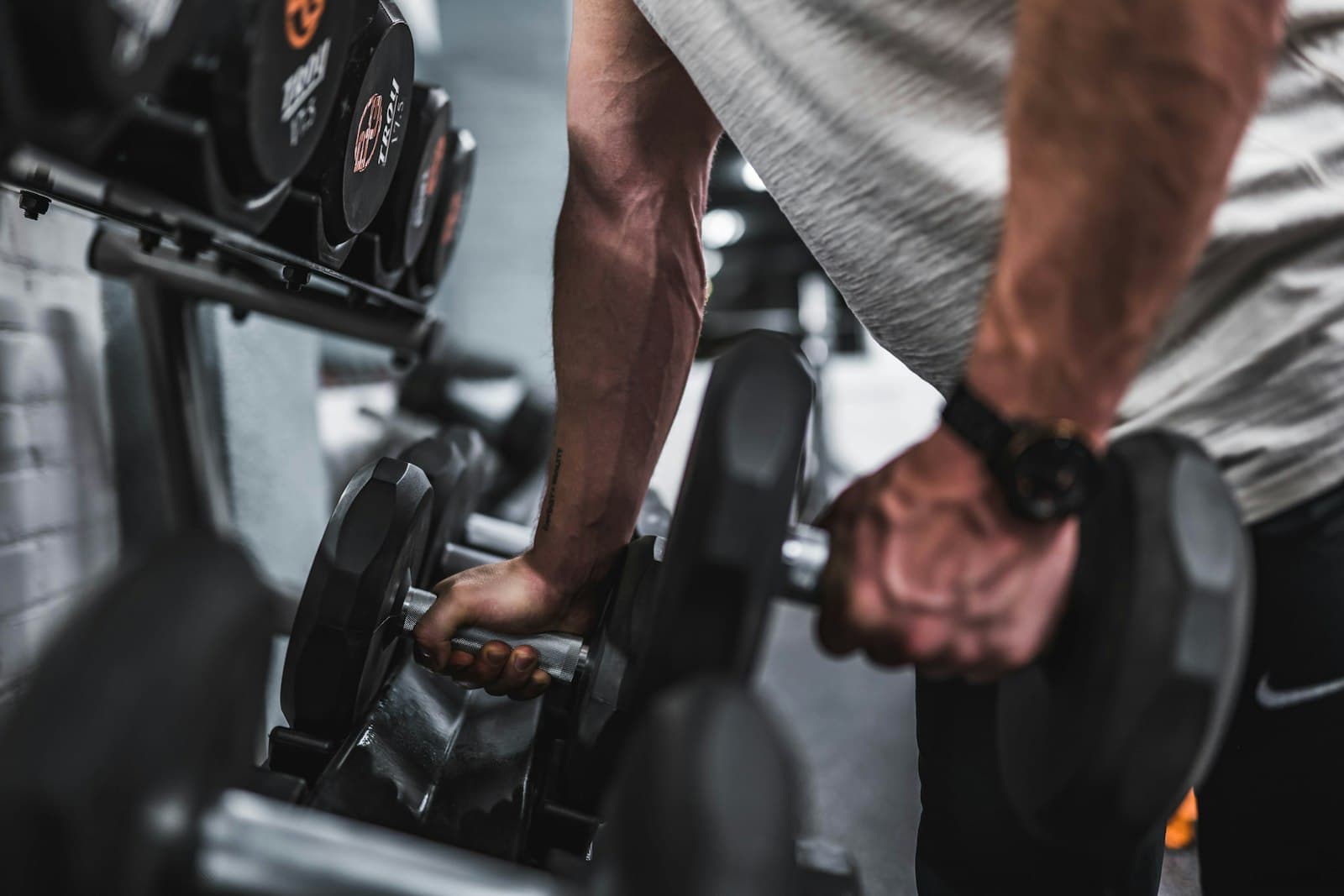 Close-up of a coach spotting a client's dumbbell rack pull